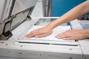 hands putting a sheet of paper into a copying device